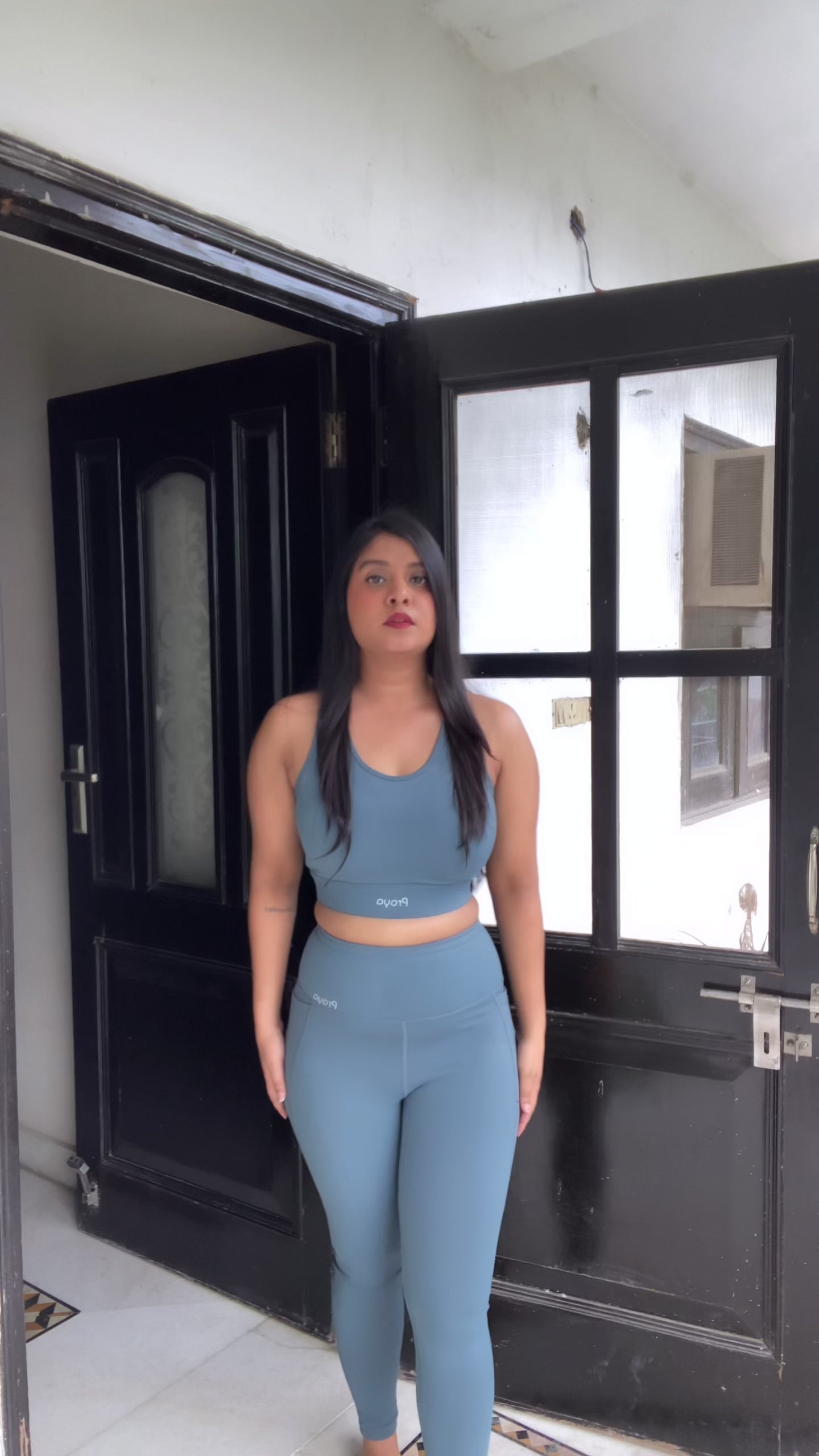Load video: Women wearing the High-Waisted Everyday Basic pocket tights ,Paired with high impact ,fully paded criss cross sports bra , posing and moving in at random space  setting to showcase the fitted silhouette, stretch fabric, and supportive design.